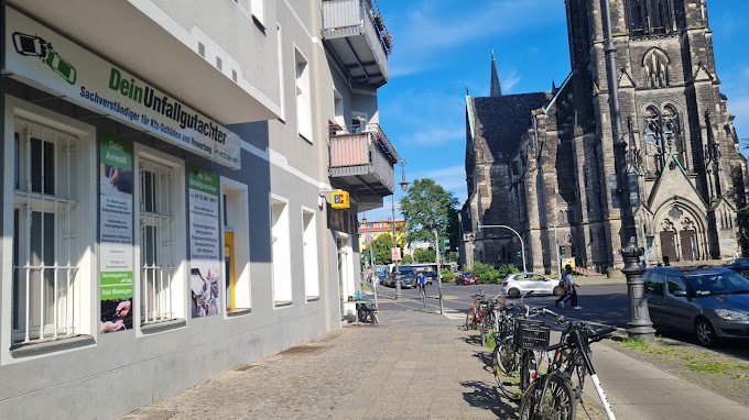 Straßenansicht der Gneisenaustraße mit dem Büro von Dein Unfallgutachter und der Kirche am Südstern