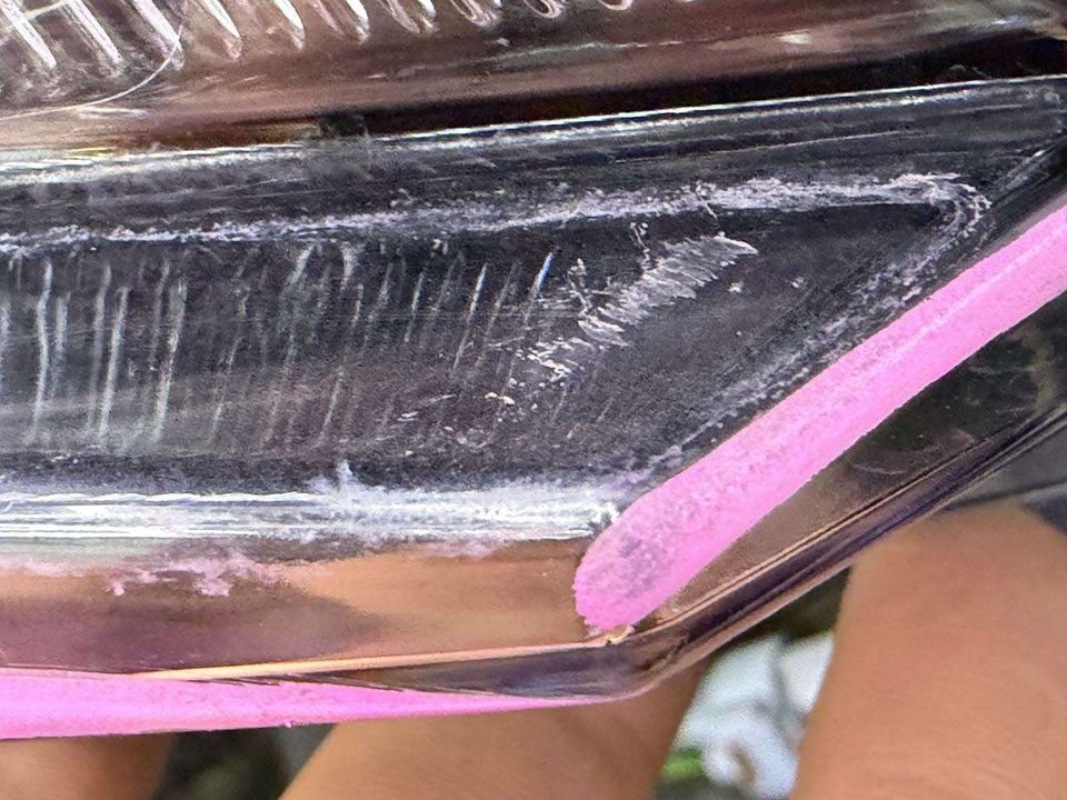 Nahaufnahme der Unterseite des LED-Scheinwerfers: tiefe Kratzer und Verformungen im Gehäuse, mit rosa Kreide markiert
