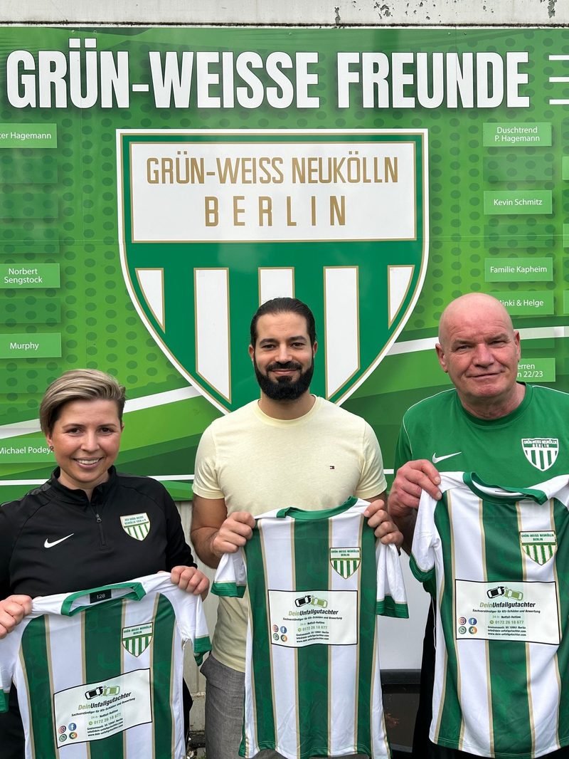 Übergabe der neuen Trikots mit dem Logo von Dein Unfallgutachter vor der Vereinswand von Grün-Weiss Neukölln